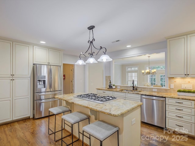 kitchen with sink, a kitchen island, decorative light fixtures, and appliances with stainless steel finishes