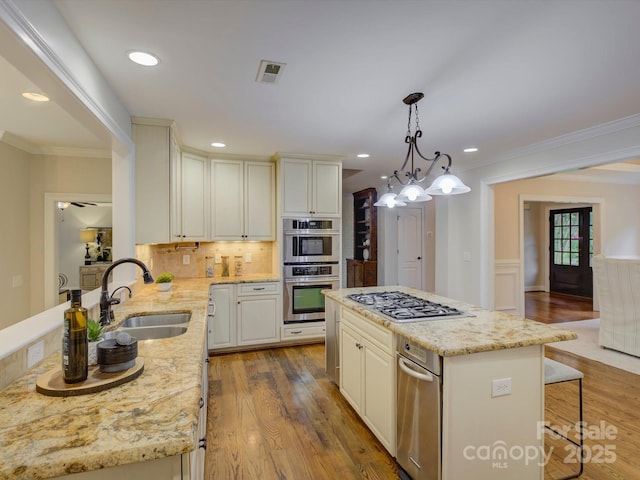 kitchen featuring sink, decorative light fixtures, decorative backsplash, a kitchen island, and appliances with stainless steel finishes