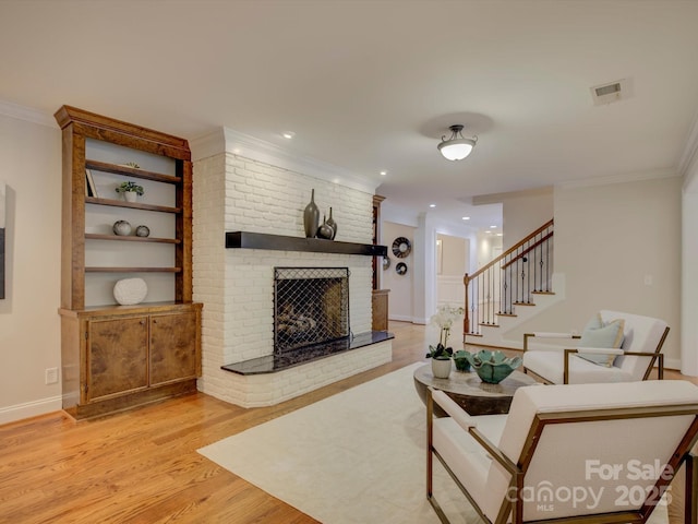 living room featuring light hardwood / wood-style floors, crown molding, and a fireplace