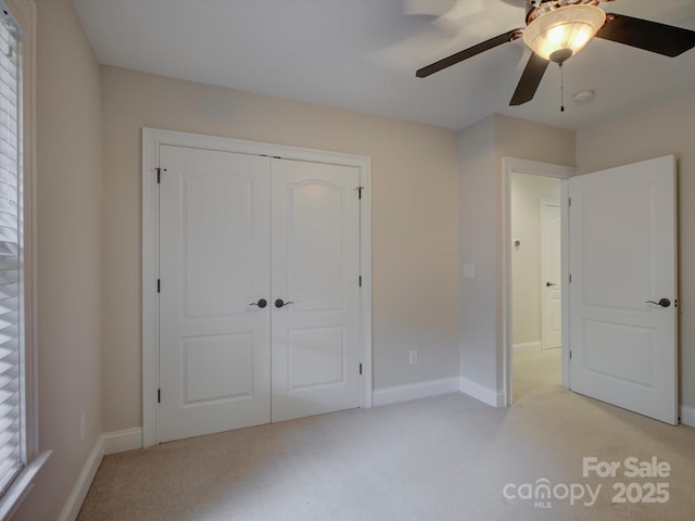 unfurnished bedroom featuring ceiling fan, a closet, and light carpet