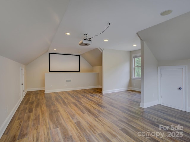 additional living space with wood-type flooring and vaulted ceiling