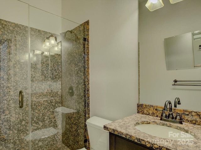 bathroom featuring a shower with door, vanity, and toilet