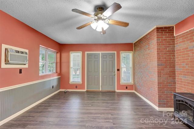 entryway with a textured ceiling, dark wood-type flooring, brick wall, a wood stove, and a wall mounted air conditioner