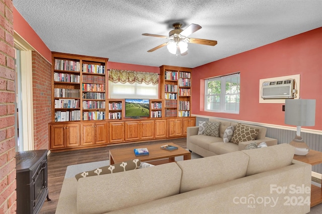 living room with dark hardwood / wood-style flooring, a textured ceiling, ceiling fan, a wall unit AC, and brick wall