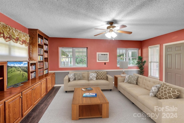 living room featuring ceiling fan, a textured ceiling, a wall mounted AC, and hardwood / wood-style flooring