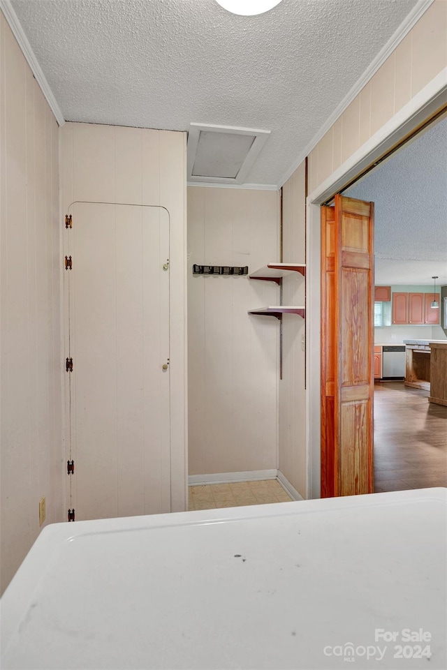 interior space with hardwood / wood-style flooring, a textured ceiling, stainless steel dishwasher, and ornamental molding