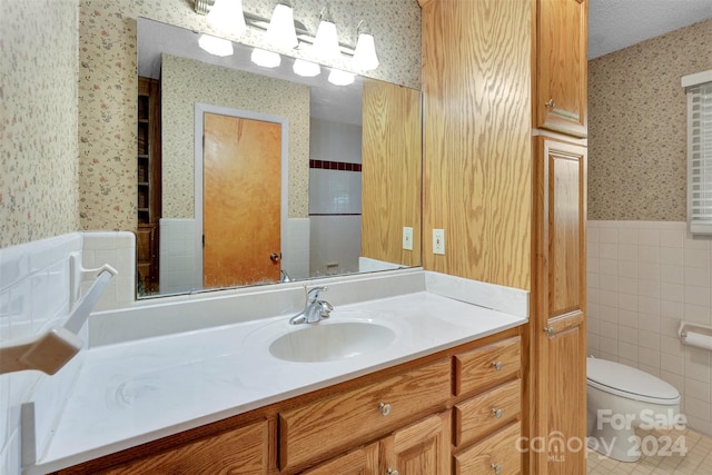 bathroom featuring a textured ceiling, toilet, tile patterned flooring, tile walls, and vanity