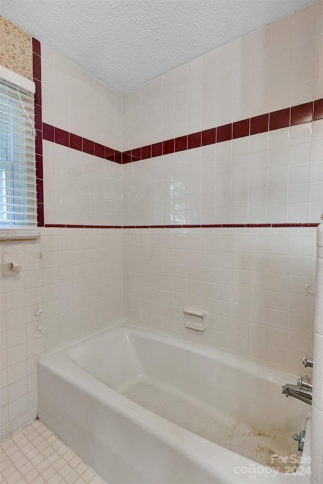 bathroom with tile walls, a textured ceiling, tiled shower / bath combo, and tile patterned floors