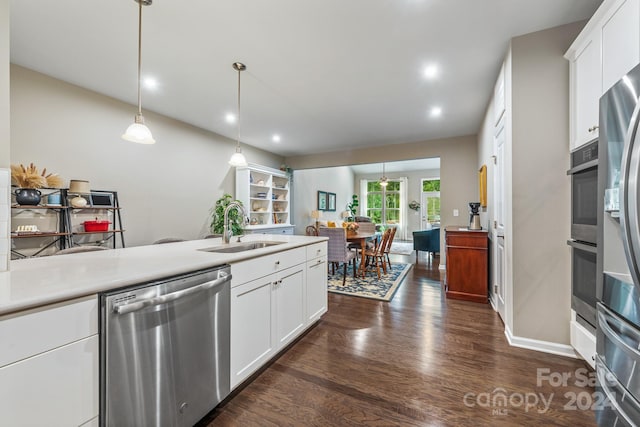 kitchen with appliances with stainless steel finishes, decorative light fixtures, dark wood-type flooring, and sink