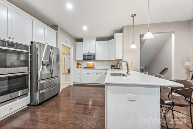 kitchen featuring a breakfast bar, dark hardwood / wood-style floors, stainless steel appliances, sink, and decorative backsplash