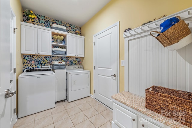 clothes washing area with cabinets, light tile patterned floors, and independent washer and dryer