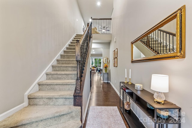 stairs featuring hardwood / wood-style flooring and a towering ceiling