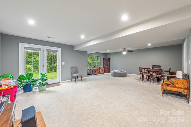 living area featuring carpet flooring, a wealth of natural light, and ceiling fan