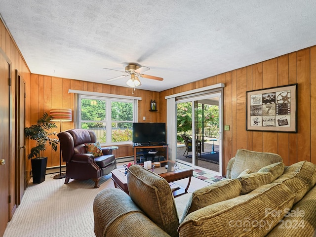 living room featuring a textured ceiling, baseboard heating, ceiling fan, and carpet floors