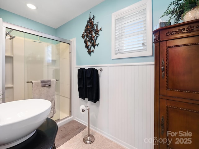 full bathroom featuring tile patterned flooring, a shower stall, and wainscoting