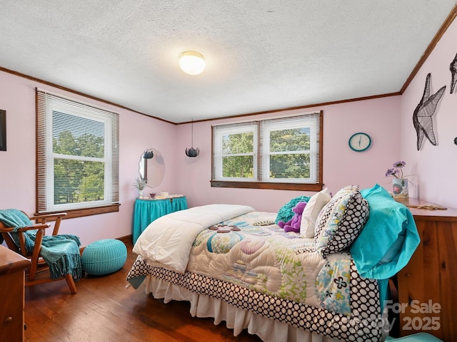 bedroom with wood finished floors, a textured ceiling, ornamental molding, and multiple windows