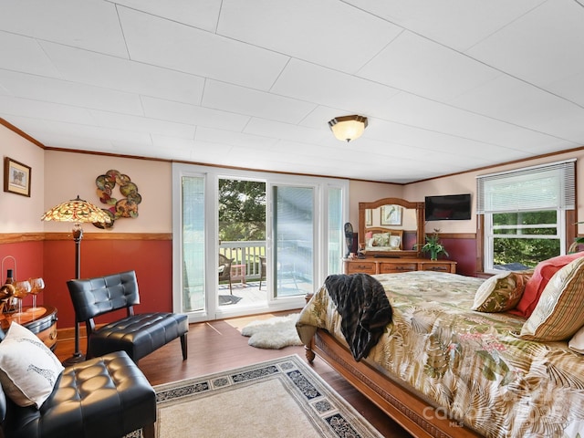 bedroom featuring access to exterior, wood finished floors, multiple windows, and crown molding