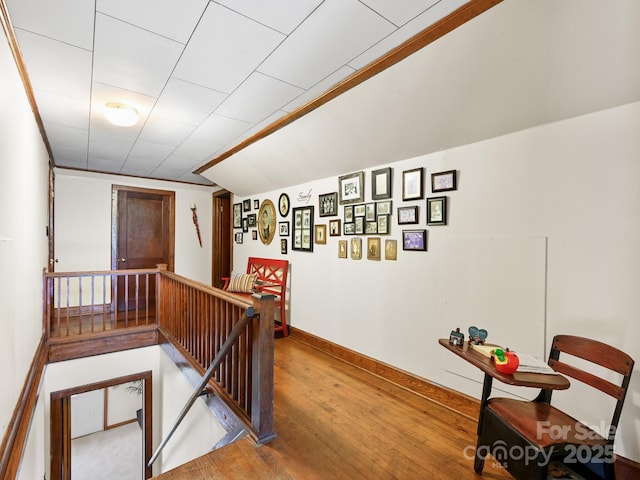 hallway featuring an upstairs landing, wood finished floors, and baseboards