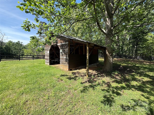 view of outdoor structure with fence and an outbuilding