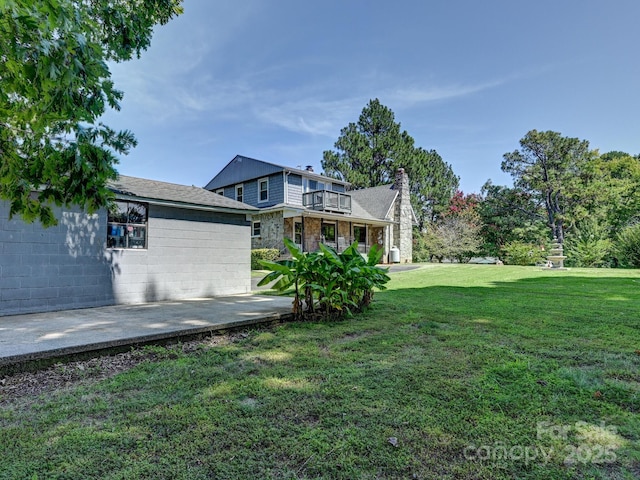 view of side of home with a lawn, a patio, and a balcony