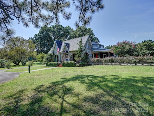 view of front of home featuring fence, a front yard, and stone siding