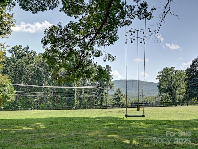 view of community featuring a mountain view, a yard, and fence