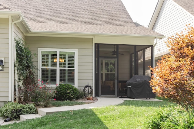 doorway to property with a shingled roof and a lawn