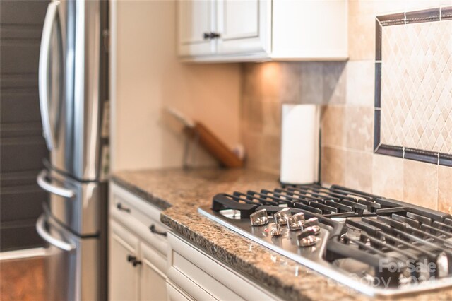 kitchen featuring dark stone counters, white cabinetry, stainless steel refrigerator, and tasteful backsplash