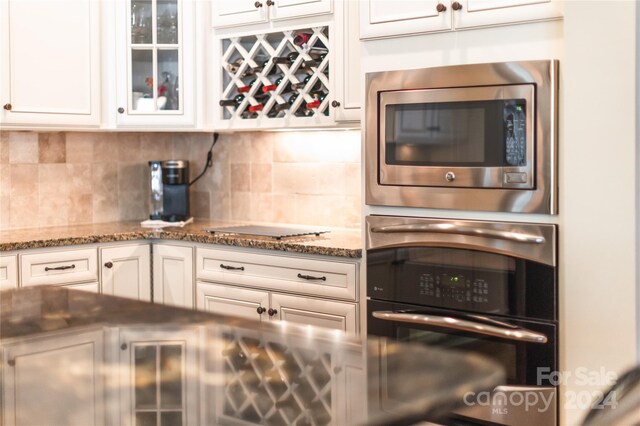 kitchen featuring dark stone counters, appliances with stainless steel finishes, tasteful backsplash, and white cabinets