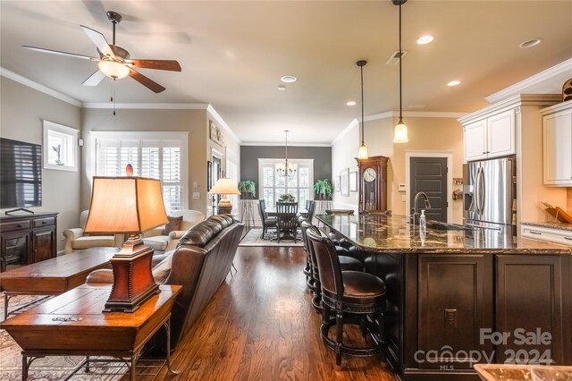 kitchen featuring dark stone countertops, crown molding, dark wood-type flooring, and stainless steel refrigerator with ice dispenser