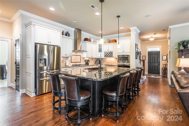 kitchen with dark hardwood / wood-style flooring, decorative backsplash, stainless steel appliances, crown molding, and wall chimney range hood