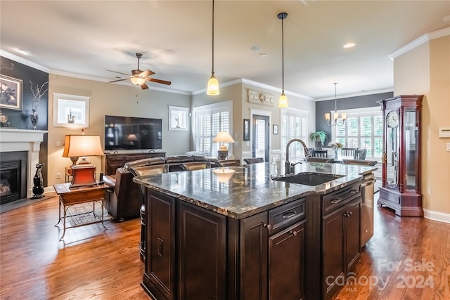 kitchen featuring crown molding, a glass covered fireplace, a sink, dark brown cabinetry, and wood finished floors