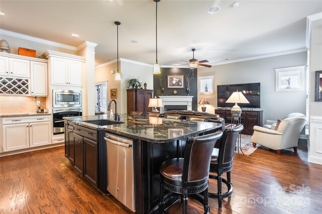 kitchen featuring ceiling fan, dark wood-type flooring, dark stone countertops, crown molding, and stainless steel appliances