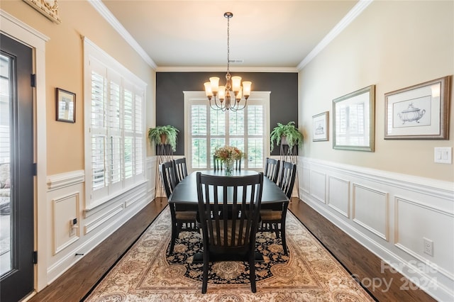 dining area with visible vents, wainscoting, dark wood-style flooring, an inviting chandelier, and crown molding