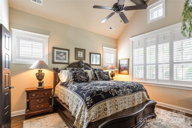 bedroom with hardwood / wood-style floors, lofted ceiling, ceiling fan, and multiple windows