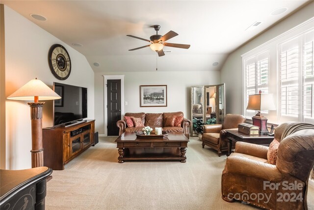 carpeted living room with ceiling fan and vaulted ceiling