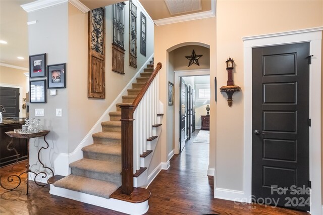 staircase with ornamental molding and wood-type flooring