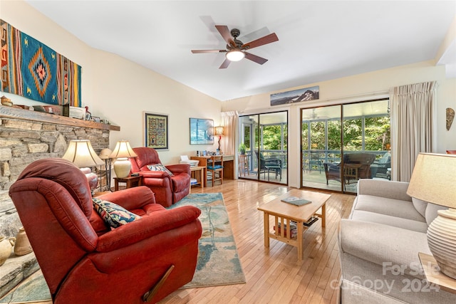 living room with ceiling fan, a fireplace, vaulted ceiling, and light hardwood / wood-style floors