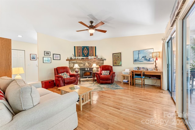 living room featuring a fireplace, light wood-type flooring, and ceiling fan