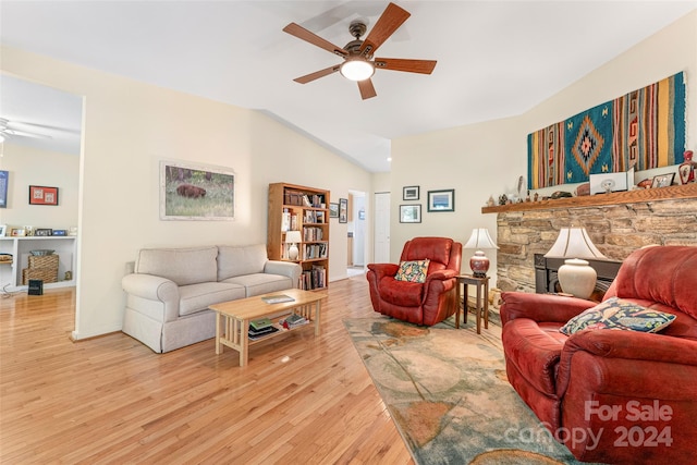 living room featuring a stone fireplace, ceiling fan, and light hardwood / wood-style floors