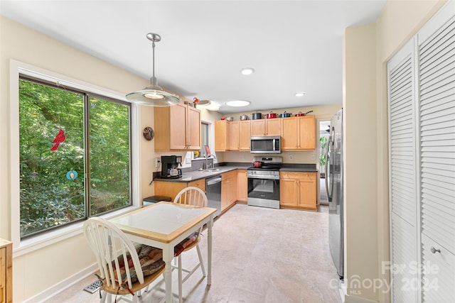 kitchen featuring light brown cabinetry, pendant lighting, light tile patterned floors, appliances with stainless steel finishes, and sink