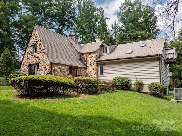 exterior space featuring central air condition unit, stone siding, a yard, roof with shingles, and a chimney