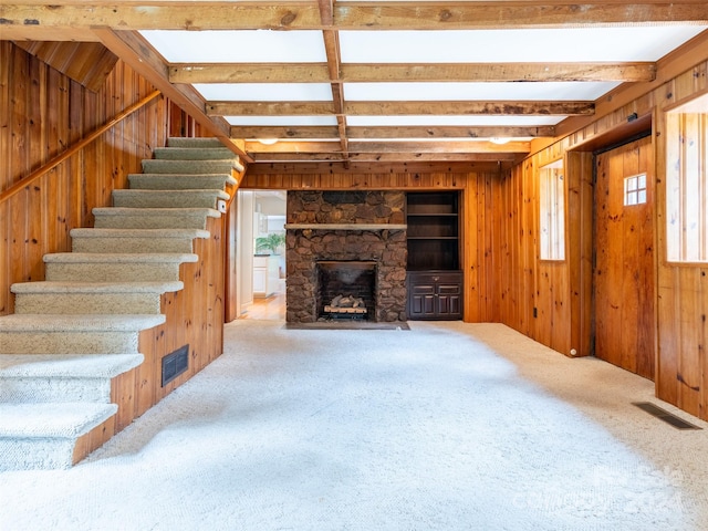 unfurnished living room featuring wooden walls, a fireplace, plenty of natural light, and carpet flooring