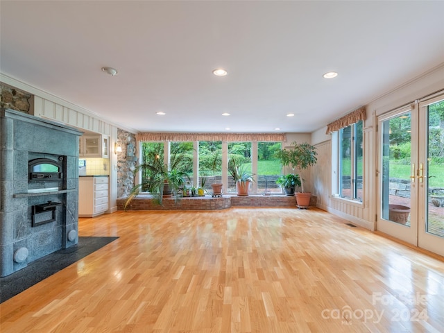 unfurnished living room with light hardwood / wood-style flooring, a large fireplace, and ornamental molding