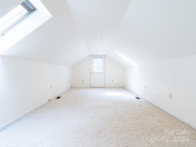 bonus room with vaulted ceiling with skylight and carpet flooring