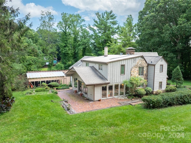 127 Springside Rd, Asheville, NC 28803 - rear view of property featuring board and batten siding, a lawn, a chimney, a patio area, and stone siding