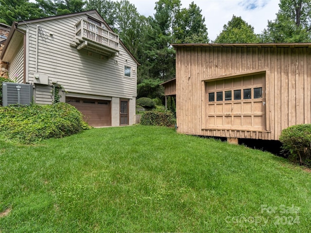 exterior space featuring a lawn, cooling unit, and a garage