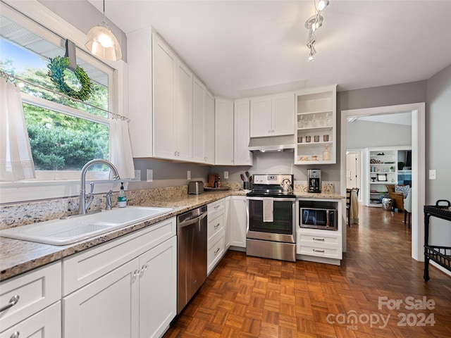 kitchen featuring dark parquet floors, stainless steel appliances, hanging light fixtures, white cabinets, and sink