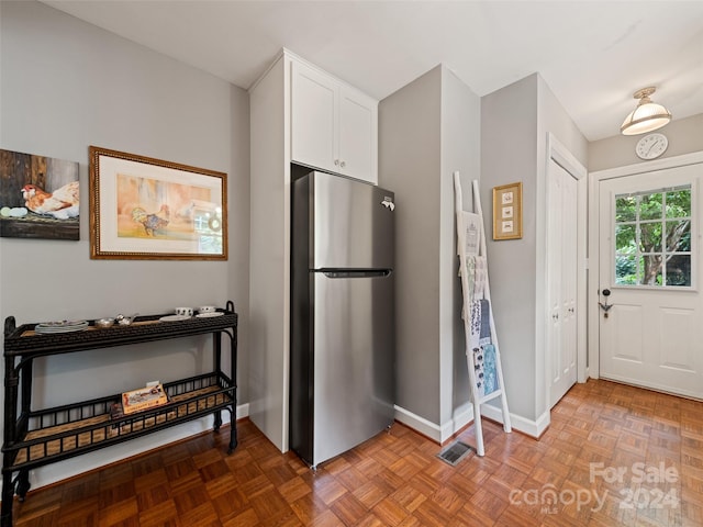 kitchen featuring white cabinets, parquet flooring, and stainless steel refrigerator