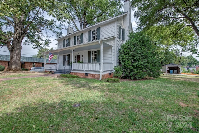 view of front of house with covered porch, crawl space, a detached carport, a chimney, and a front yard